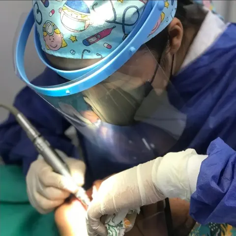 Dariana con careta y gorro quirúrgico trabajando con la turbina dental